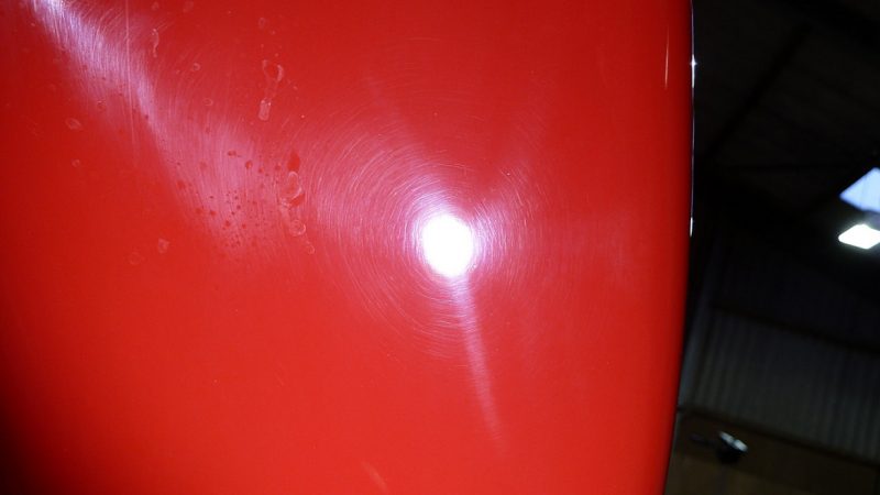 Sanding marks and buffer trails in the Guards Red paint under inspection light