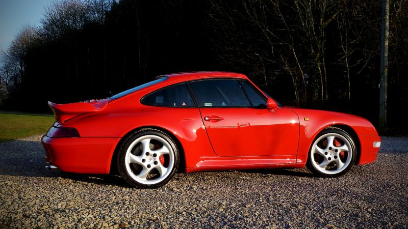 Porsche 993 Carrera 4S side on, Guards Red glowing against the treeline