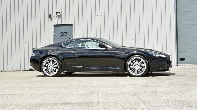 Side profile of the black Aston Martin DBS after its machine polish
