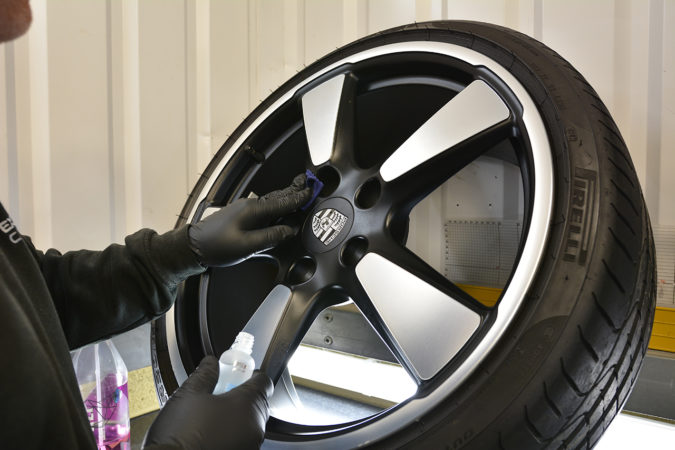 Polished-spoke 50th Anniversary wheel being cleaned and coated away from the car