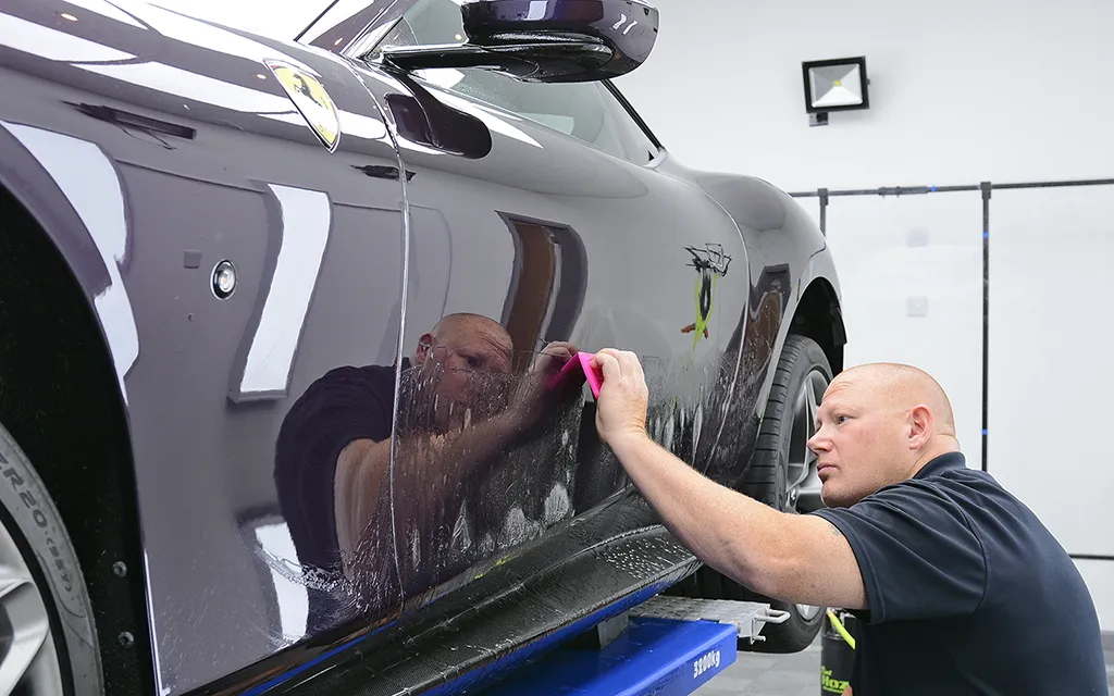 Technician applying Xpel PPF to passenger door on Ferrari Roma