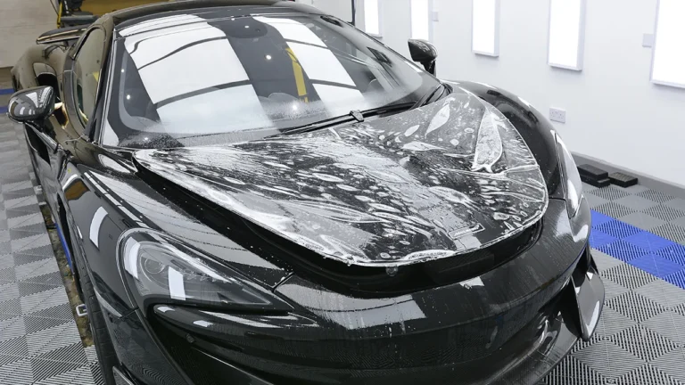 XPEL paint protection film being applied over the nose and bonnet of the black McLaren 600LT